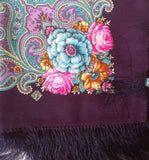 Colorful floral and paisley patterned fabric with fringes on a dark background