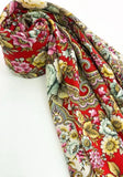 Colorful red woolen shawl with floral and paisley patterns on a white background. Close-up texture view of a cozy red merino wool palantine sample filled with colorful pink, yellow, and green folk ornaments.