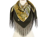 Scarf with green and gold pattern and black fringes on a mannequin against a white background