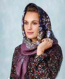 Woman wearing a patterned blue cashmere head scarf with a plain background