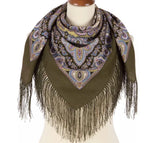 Olive green scarf with paisley pattern and fringes on a mannequin against a white background