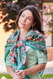 Woman wearing a colorful mint green and pink woolen square shawl outdoors with blurred background