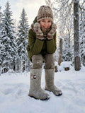  A pair of premium handcrafted Slavic winter boots worn outdoors on a thick blanket of snow. The design stands out due to its elongated, structured wide shaft profile, crafted from dense 100 percent natural wool felt in a soft heather beige colorway. Embroidered into the side of the shaft is a large, folk-inspired floral motif in shades of deep brown, cream, and white, while a durable, heavy-duty black and beige rubber outsole serves as the weather-resistant foundation.