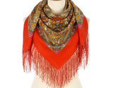 Orange scarf with a patterned merino wool shawl with fringe  draped over it on a mannequin against a white background