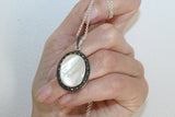 Oval vintage lightweight pendant with shell stone in ivory and marcasite stones a rround in a woman hand,