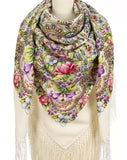Colorful floral and paisley patterned scarf with tassels on a mannequin against a white background