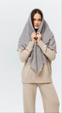 A woman wearing a charcoal gray winter wrapping shawl on her head and shoulders and showing the texture and goat down fluffy feelings.