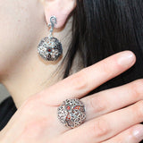 A woman`s photo showing a pomegranate earring and a dome pomegranate ring on a finger.