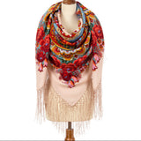 A wrapping shawl in beige with red large flowers and fringe on a white background.