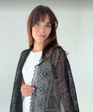 A narrow rectangular woolen black pashmina styled as a lightweight palatine , its delicate, lace-like premium texture visible on a woman`s shoulders.
