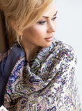 Woman wearing a lavender purple patterned scarf with a neutral background