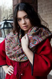 Woman wearing a colorful patterned Slavic scarf and red coat outdoors.