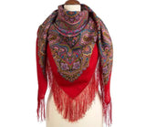 Red merino wool scarf with intricate paisley pattern and fringes on a mannequin against a white background