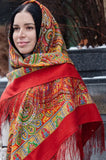 Woman wearing a colorful Slavic  traditional head scarf with intricate patterns in orange red color with yellow and green ornaments.