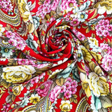 Colorful red floral merino wool shawl swatch with floral and paisley patterns on a red background. A close-up swatch of a red merino wool shawl with colorful peony yellow floral and paisley patterns.