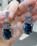 A navy blue stone Armenian handmade  ring and earrings set with silver marcasite details, held in a person's hand.
