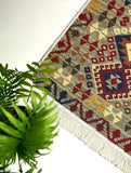 Patterned Armenian taraz rug with geometric design and green plant on a white background