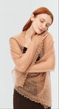 A cozy winter look featuring a woman wrapped in a warm, gossamer-soft light brown pashmina shawl.