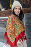 Woman wearing a colorful orange red patterned shawl and beige knit hat in a snowy setting
