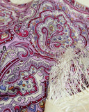 Close-up of a colorful paisley patterned shawl white with purple pattern and fringes with tassels.