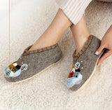 Gray slippers with snowman design on a beige carpet