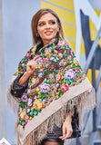 Woman wearing a colorful embroidered shawl with floral patterns in an urban setting.