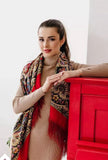 Woman wearing a patterned woolen red scarf and beige sweater against a white background