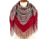 Red woolen scarf with paisley pattern and fringes on a mannequin against a white background