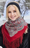 Woman wearing a red woolen scarf with ethnic patterns and long fringe in a snowy outdoor setting