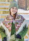 Woman wearing a floral merino wool Slavic shawl, green hat, and gloves in a snowy outdoor setting.