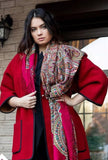 Woman wearing a red coat with a patterned large Slavic scarf outdoors.