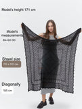 An over-the-shoulder view of an oversized hand-knitted black pashmina  winter shawl for women bundled tight against a snowy backdrop. The styling illustrates its practical warmth and generous diagonal stretch of 155 cm.