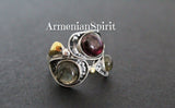 A photo showcasing a silver unusual ring with 3 gemstones and gold plated details on a black surface.