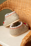 A view of two handmade white felted wool slip-on loafers for indoor wear, showcasing deep red bird embroidery. The design highlights a spacious and wide toe area that forms to the wearer's foot, blending medical health benefits with modern lifestyle aesthetics.