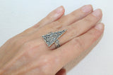 A picture displaying a hand with a triangle ring on the middle finger which has an ethnic design with unusual sun ornaments.