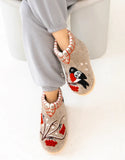 Pair of decorative woolen bootie slippers with bird and floral design on a white background