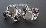 A pair of silver earrings featuring natural garnet and labradorite gray gemstones, with gold plating on the metal.