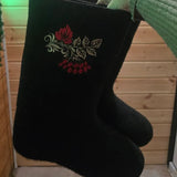 Elegant product presentation of traditional Slavic black felt boots designed for extreme freezing weather up to minus 35 degrees. The boots stand vertically in crisp white winter snow, showcasing the rich contrast between the dark black wool felt and the vivid red rowan berry embroidery, capturing an authentic heritage style adapted for modern winter apparel collections.