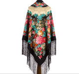 A large winter shawl crafted from natural merino wool, featuring a black hem with a long fringe and a vibrant traditional pattern of large vintage flowers, pink peonies, and blue wildflowers with a yellow center.