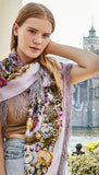 Woman wearing a decorative floral scarf with a blurred cityscape in the background