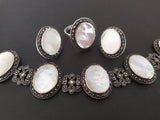 A set of sterling silver jewelry including Armenian earrings, a ring, and a old vintage style bracelet with natural white oval stones and marcasite details.