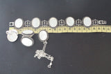 A photo displaying a bracelet, earrings, ring and a pendant in oval shape with marcasite and shell flat stones near a yellow ruler on a black surface.