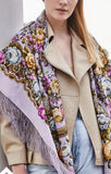 Person wearing a floral pale purple shawl over a beige coat with a blurred background