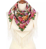 Red and yellow floral patterned white woolen scarf with fringes on a mannequin against a white background