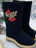 Premium black valenki boots that feature an intricate red rowan berry folk embroidery patch on the wide shaft. Side profile of authentic black sheep wool felt winter boots being worn outdoors on a crisp winter day. The modern design highlights a thick, protective rubber outsole with a light-colored midsole strip that perfectly offsets the deep, matte black wool body.