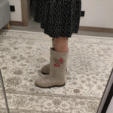 Fashionable handmade one of a kind woolen boots with rubber outsole and red rowanberry embroidery in Slavic valenki style on a carpet near a mirror.