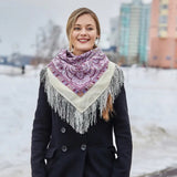 Woman wearing a purple patterned merino wool scarf  neck warmer with white fringe in an urban snowy setting