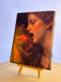Handcrafted wooden art plaque of Eve taking a bite of the forbidden apple with a coiled serpent. Dramatic biblical temptation artwork on a solid wood panel resting on a small display easel.