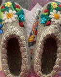 Pair of Slavic chuni slippers with floral designs on a colorful background