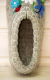 Felted slipper with floral and ladybug decorations on a wooden surface